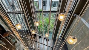 Een modern interieur met een centrale trap, metalen hekwerk en hangende pendellampen.