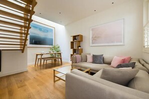 A modern living room with a sofa, coffee table, and a wooden bench. There is a bookshelf and a painting on the wall. - DO NOT Book Invalid Listing (London)