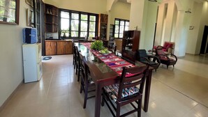 A spacious dining area with a long table, chairs, and a bookshelf.