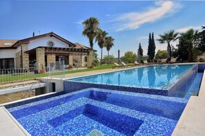Enjoy a refreshing swim in the large blue-tiled pool surrounded by a well-manicured lawn.
