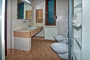 Bathroom features a dual sink vanity, toilet, and glass shower enclosure.