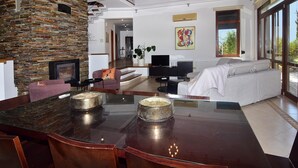 A modern living room with a stone accent wall, a dining area with a glass-top table, and a sofa set. - Incredible Large Villa, Paphos, 6 bedrms BBQ Huge Pool Childrens pool Quiet area (2CQW+J39 Poli Crysochous, Cyprus)