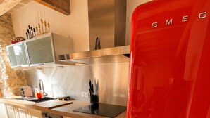 Une cuisine avec un réfrigérateur rouge, des armoires en bois, une hotte de cuisine en acier inoxydable et un plancher en bois.
