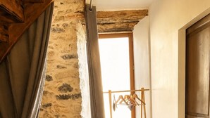 Un escalier en bois mène à une mezzanine où se trouvent un étendoir en bois et une fenêtre.