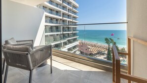 Un balcón con vista a la playa y un edificio de varios pisos.