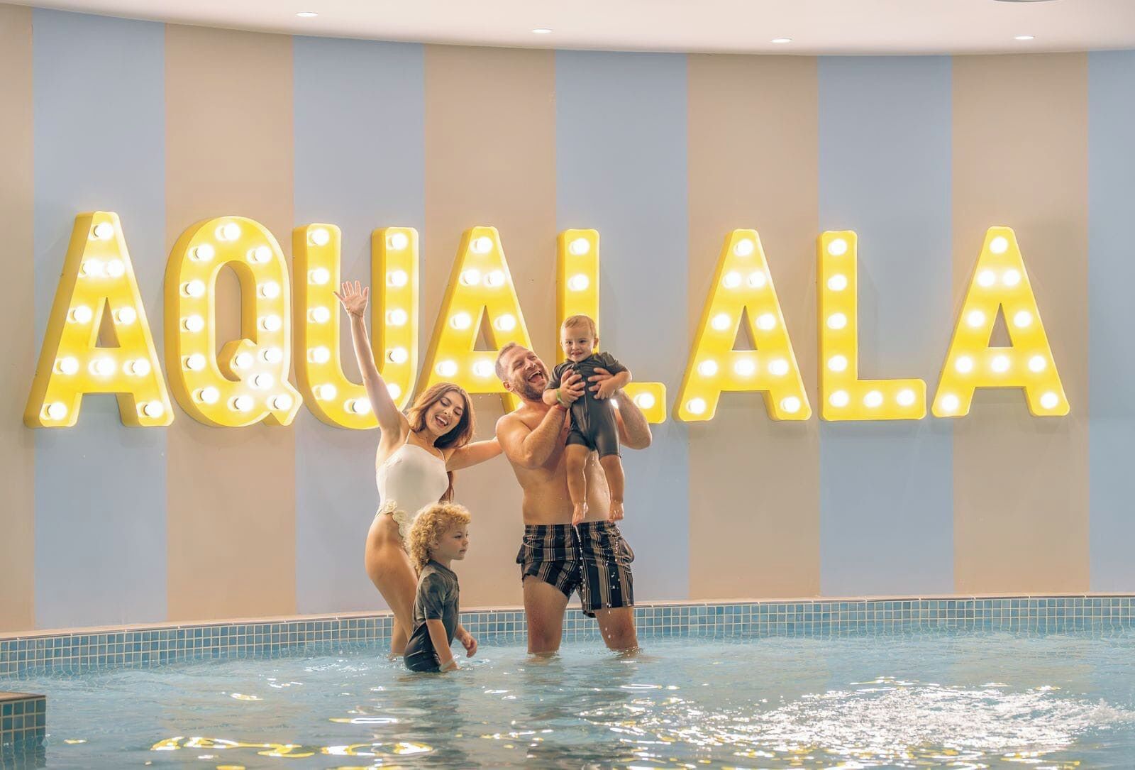 Ein Poolbereich mit beleuchteten Buchstaben, die "AQUALALA" an der Wand zeigen.
