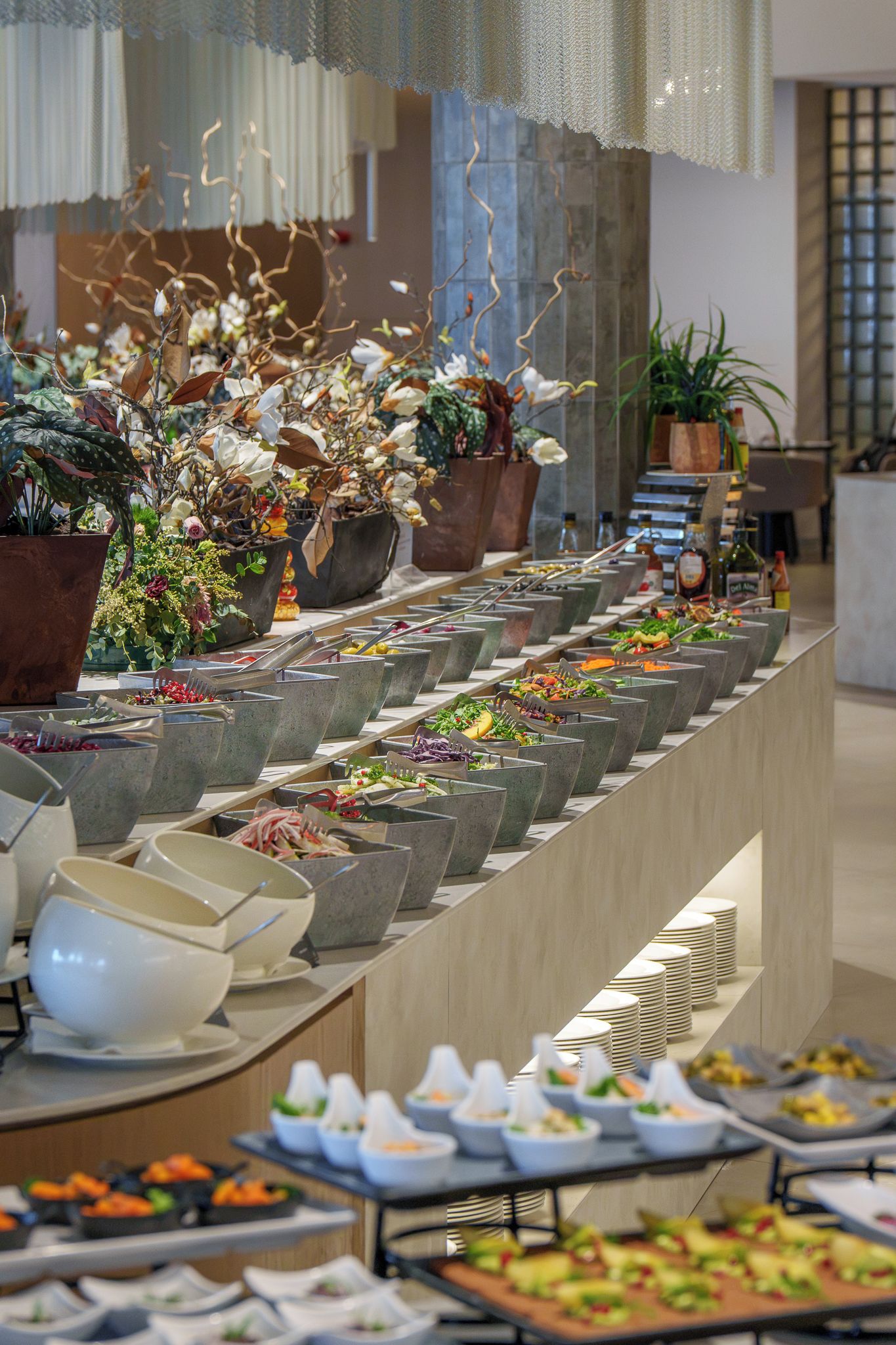 Montaje de bufé con distintas estaciones de comida y un arreglo floral decorativo.