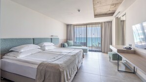 Habitación de hotel con dos camas, un escritorio, una silla y un ventanal con cortinas.