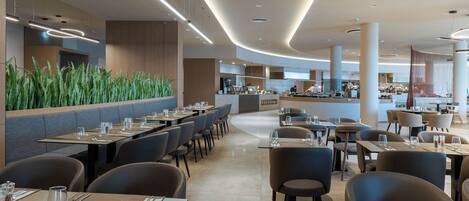 A modern restaurant with a long counter, booths, and a bar area.