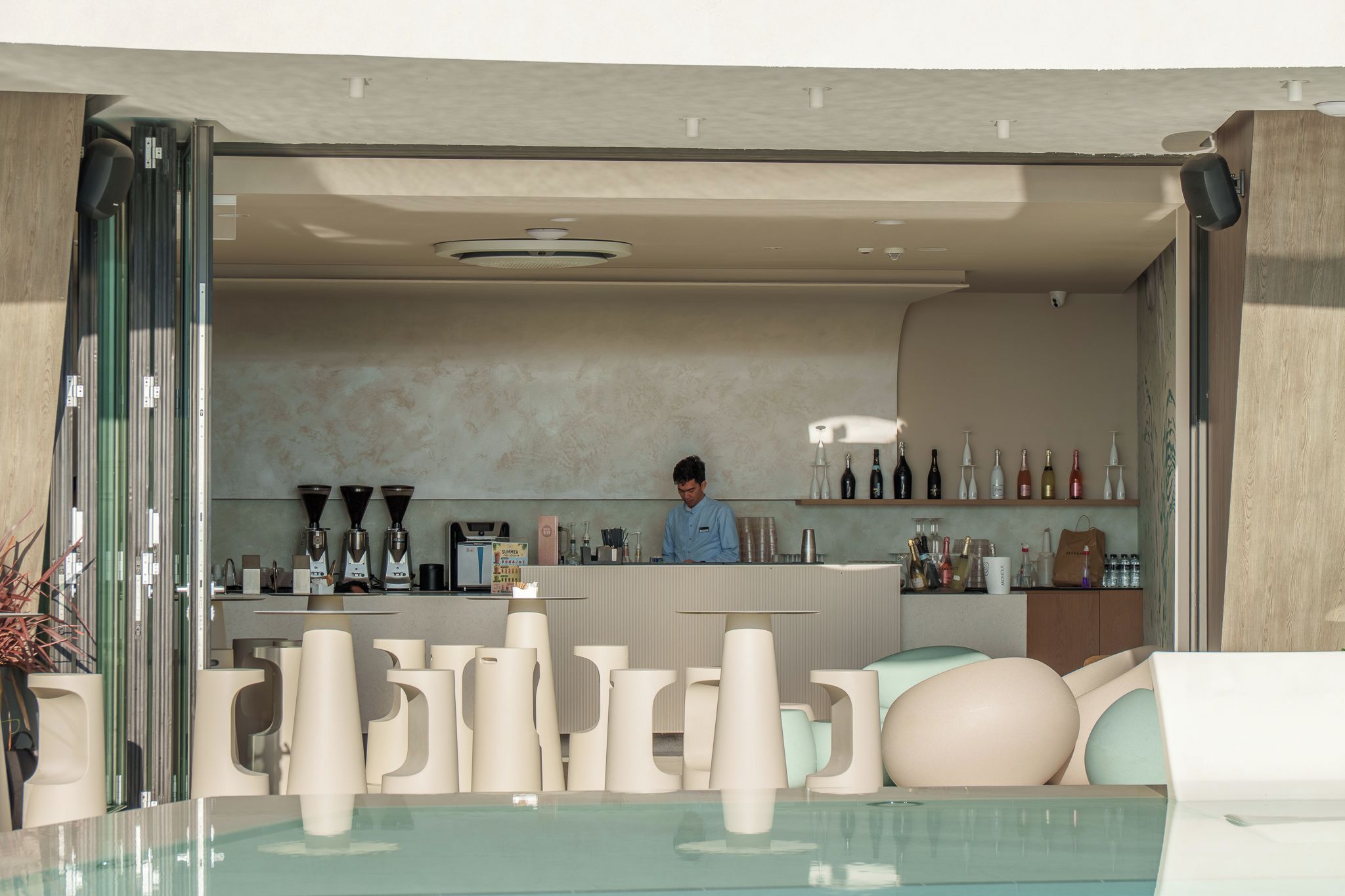 Una zona de bar con mostrador, varias botellas y una persona sirviendo.