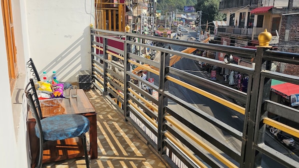 Un balcón con una mesa de madera, sillas y aperitivos.