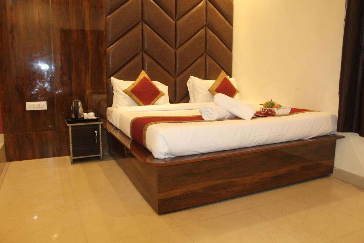 Una habitación de hotel con una cama grande, una mesita de noche y un cabecero de madera.