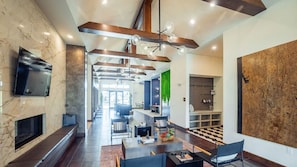 A spacious living area with a fireplace, modern furniture, and a large TV mounted on the wall.