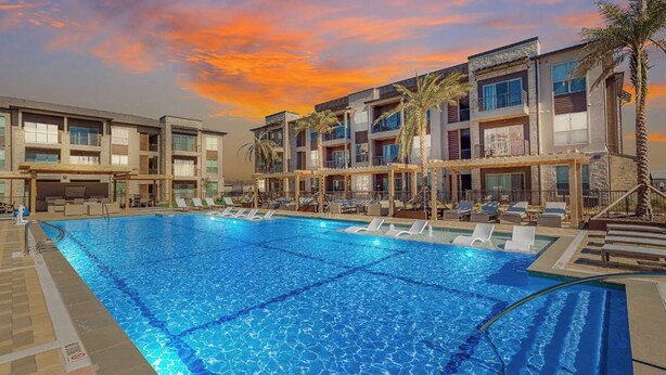 Un hotel con piscina, varios balcones y palmeras.