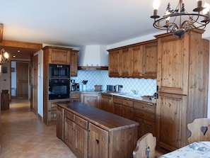 Una cocina con armarios de madera, una isla central, estufa y una araña.