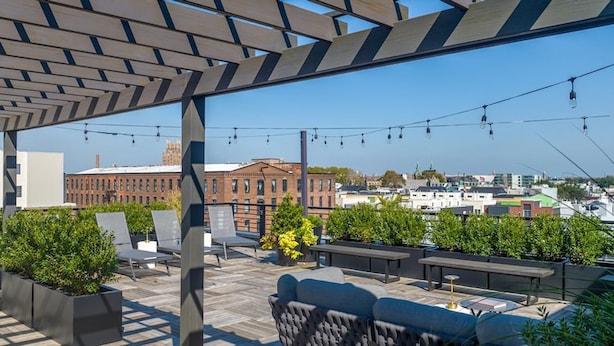 Une terrasse sur le toit, dotée d’un espace extérieur aménagé, d’une pergola et offrant une vue sur le paysage urbain.