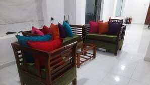 A modern living room with two wooden sofas and a small table, furnished with colorful cushions. - Island Inn Colombo00 (Colombo)