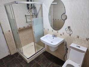 A bathroom with a glass shower enclosure, a sink, a toilet, and a mirror. - Island Inn Colombo00 (Colombo)