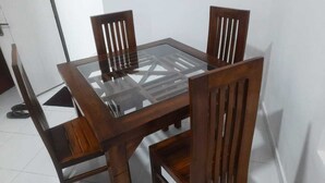 A rectangular dining table with a glass top and four wooden chairs with vertical slats. - Island Inn Colombo00 (Colombo)