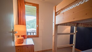 Habitación con literas, una ventana, una lámpara y un aparador de madera.