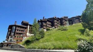 Un hotel de varios pisos con balcones, ubicado en una ladera con abundante vegetación.