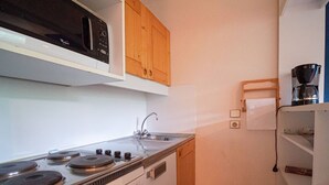 Una cocina compacta con estufa, lavamanos y armarios de madera.