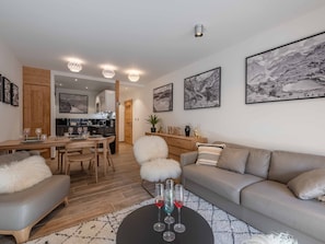 Una sala moderna con un sofá, una mesa de comedor y una cocina al fondo.