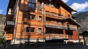 A multi-story wooden chalet with balconies, large windows, and a mountainous backdrop. - Modern 2-Bedroom Apartment in Morzine Center with Parking and Wifi (Morzine)
