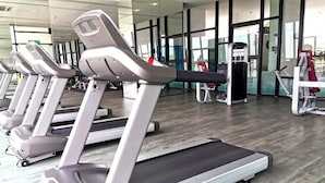 A gym with treadmills, weight machines, and a large windowed wall. - Cityview Southkey 2BR2FREE 16FL By Natol (Johor Bahru)