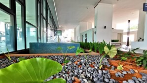 A modern indoor garden with a water feature, surrounded by large green leaves and pebbles. - Cityview Southkey 2BR2FREE 16FL By Natol (Johor Bahru)