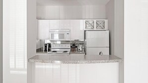 A modern kitchen with white cabinetry, a microwave, a stove, a toaster, and a refrigerator. - Landing | Stunning 1BD, Pool, Gym (Houston)
