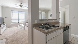 A modern kitchen with a double sink, a dishwasher, and a ceiling fan. - Landing | Stunning 1BD, Pool, Gym (Houston)