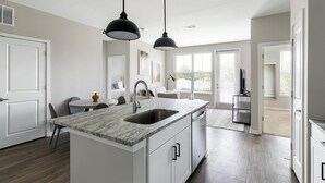 Een moderne keuken met een centraal eiland, dubbele spoelbakken en hangende lampen.