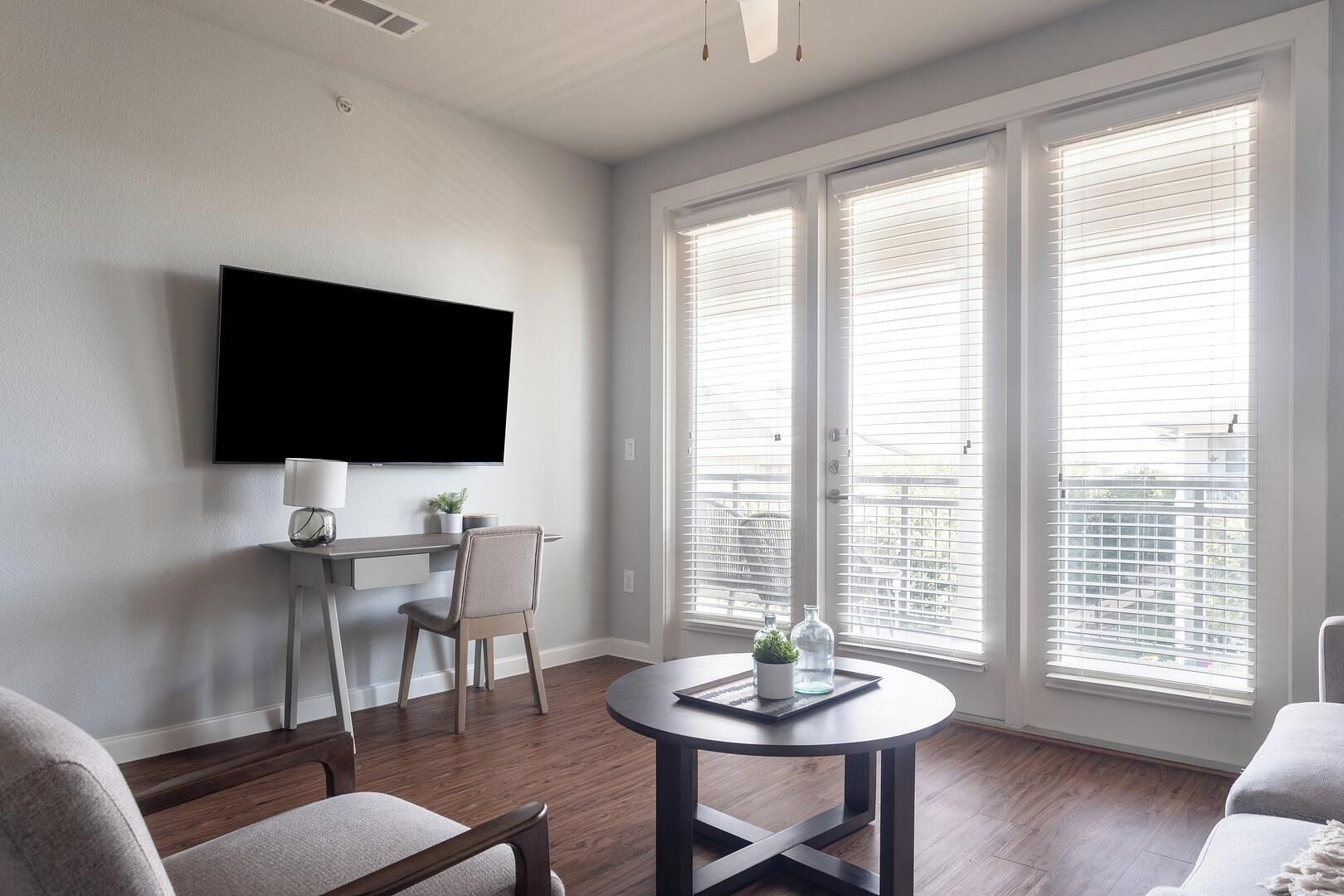 Un salon moderne avec un téléviseur à écran plat fixé au mur, une table ronde avec une lampe et un fauteuil.