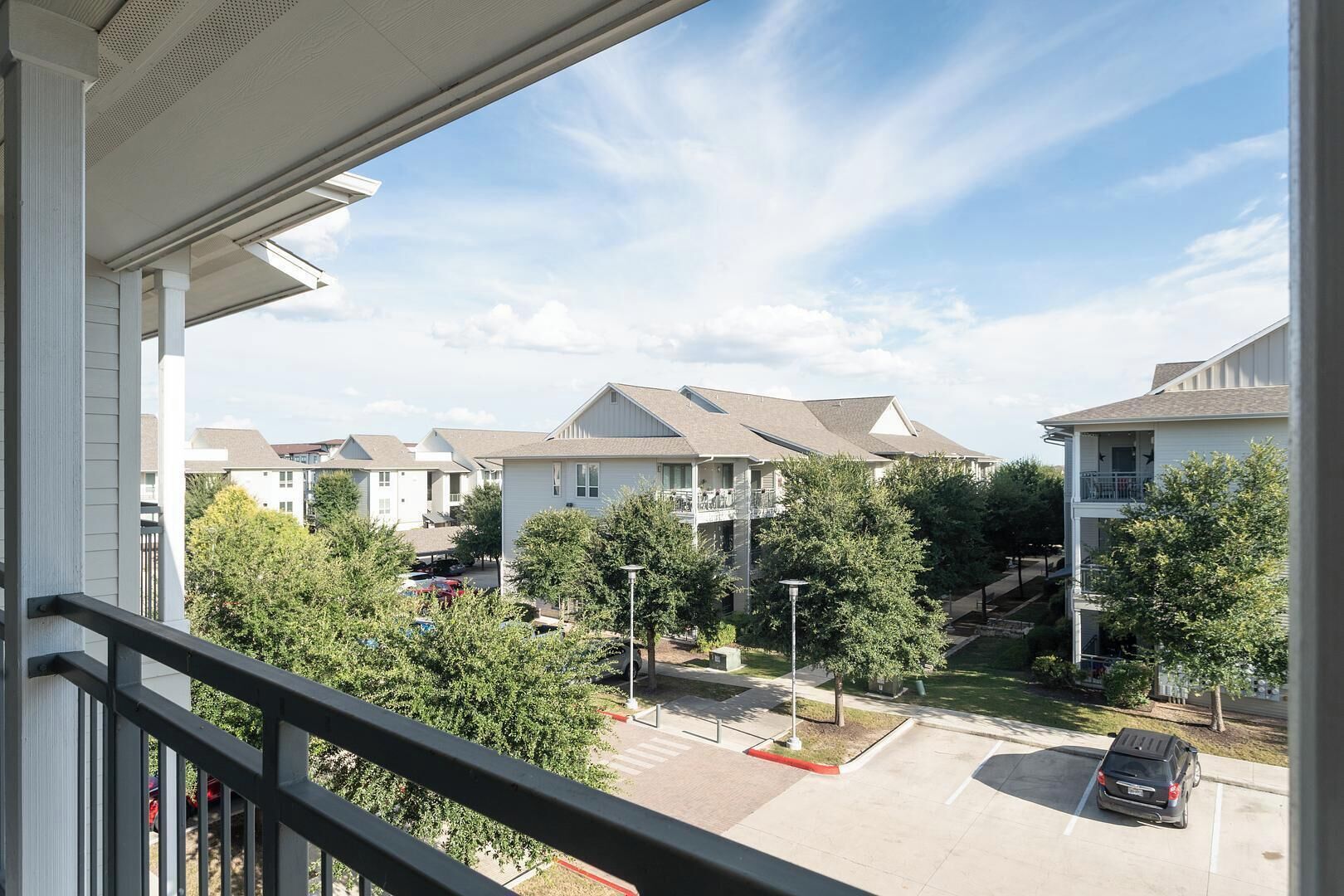 A residential area with multiple two-story houses, a parking lot, and a clear sky.
