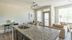 Cozinha moderna com bancadas de granito, máquina de lavar louça e área de refeições com mesa e cadeiras.