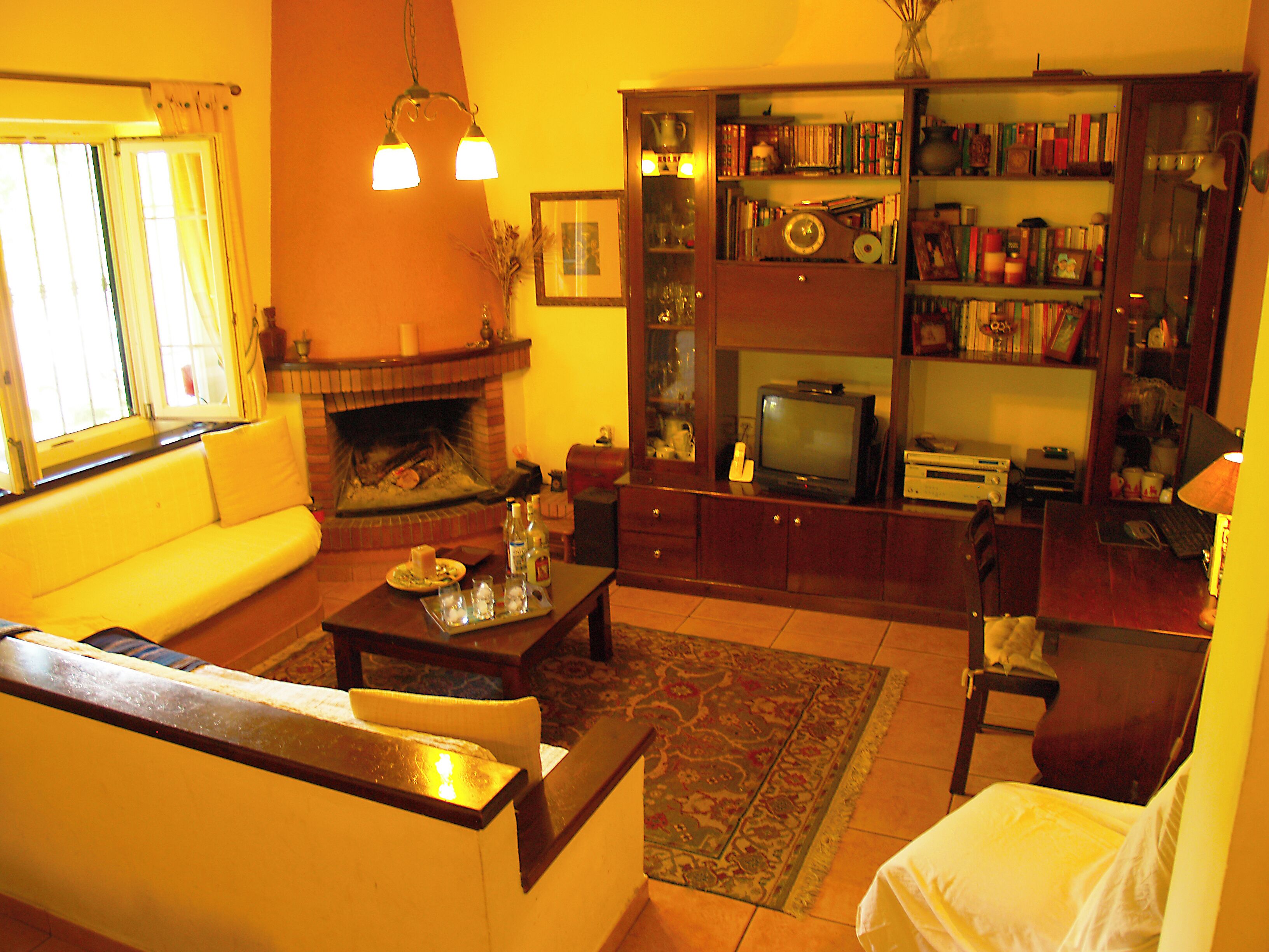 A living room with a fireplace, sofa, coffee table, and a bookshelf filled with books and decorative items.
