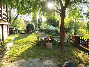 Um jardim com uma mesa de madeira, cadeiras e vasos de plantas.