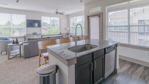 Una cocina moderna con encimera de granito, armarios oscuros y pileta de acero inoxidable.
