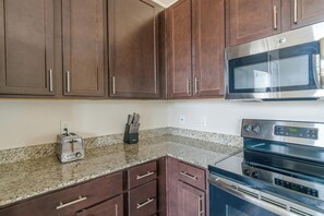 A kitchen with granite countertops, a built-in microwave, a toaster, and a double oven.