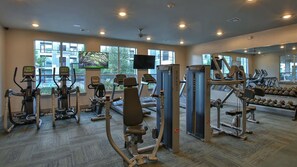 A gym with cardio machines, free weights, and dumbbells.