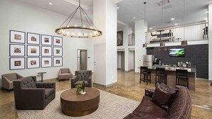 A spacious living area with a brown leather sofa, a round coffee table, and a modern chandelier. - Landing | Modern 1BD, Gym (Birmingham)