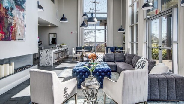 A modern hotel lobby with a seating area, a bar, and a large window offering a view of the outdoors. - Landing | Beautiful 2BD, Yoga Studio, Clubhouse (San Antonio)
