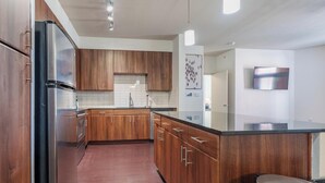 A modern kitchen with wooden cabinets, stainless steel appliances, and a black countertop. - Landing | Beautiful 2BD, Yoga Studio, Clubhouse (San Antonio)