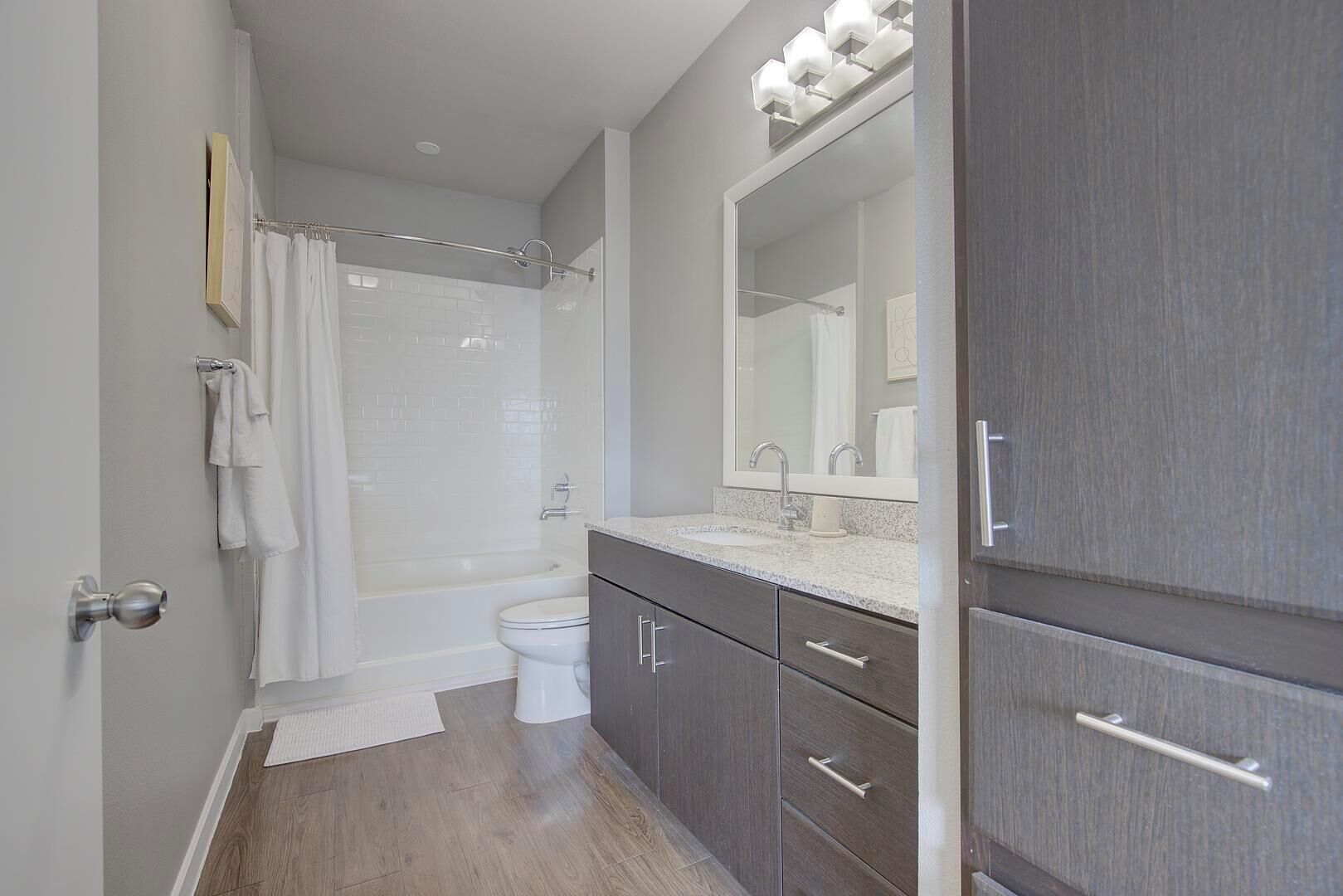 A modern bathroom with a shower, toilet, and vanity with a large mirror.