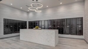 A modern lobby with a marble reception desk, black storage lockers, and circular ceiling lights. - Landing | Incredible 1BD, Yoga Studio, Gym (Salt Lake City)