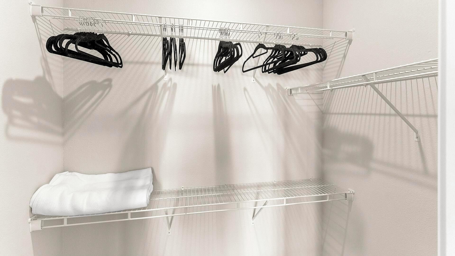 A white wall with a metal drying rack holding several black hangers.