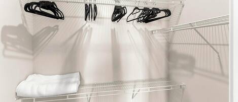 A white wall with a metal drying rack holding several black hangers.