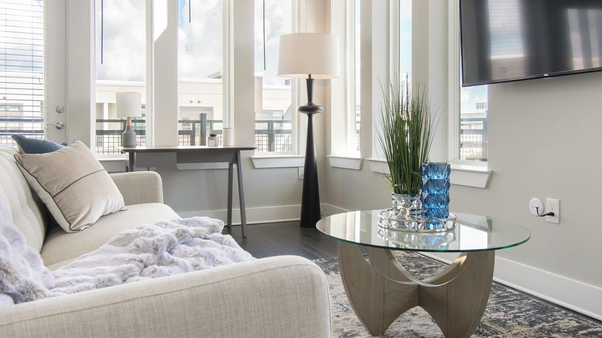 A modern living room with a sofa, a glass coffee table, and a lamp.