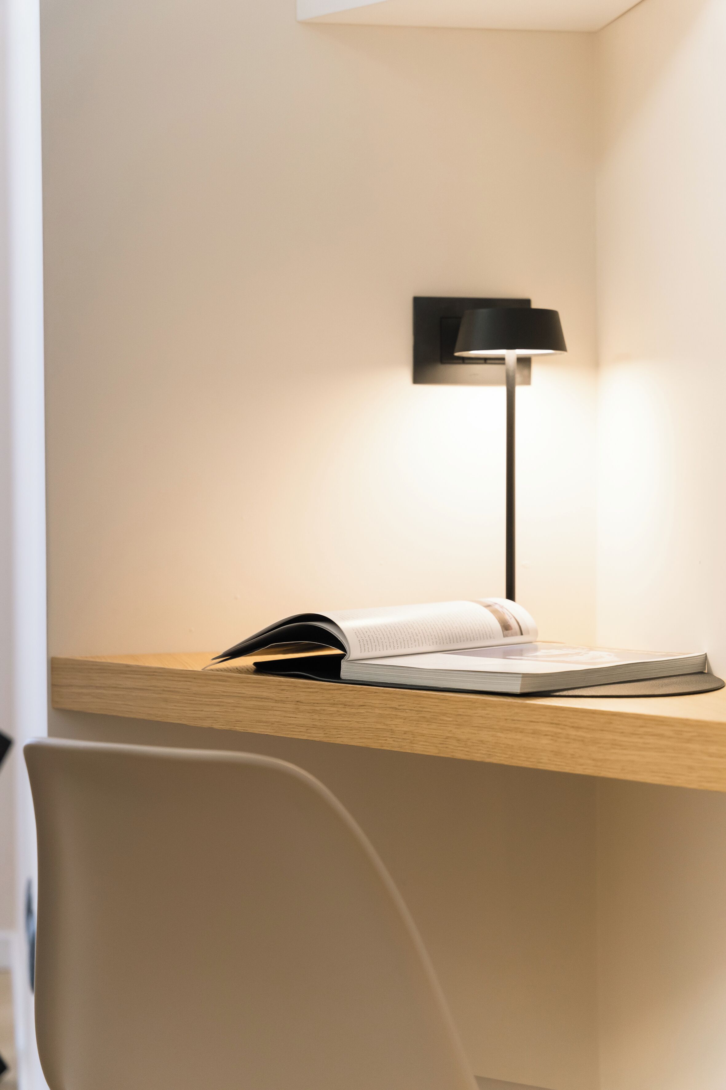 Ein moderner Schreibtisch mit einer Lampe, einem Buch und einer Zeitschrift.